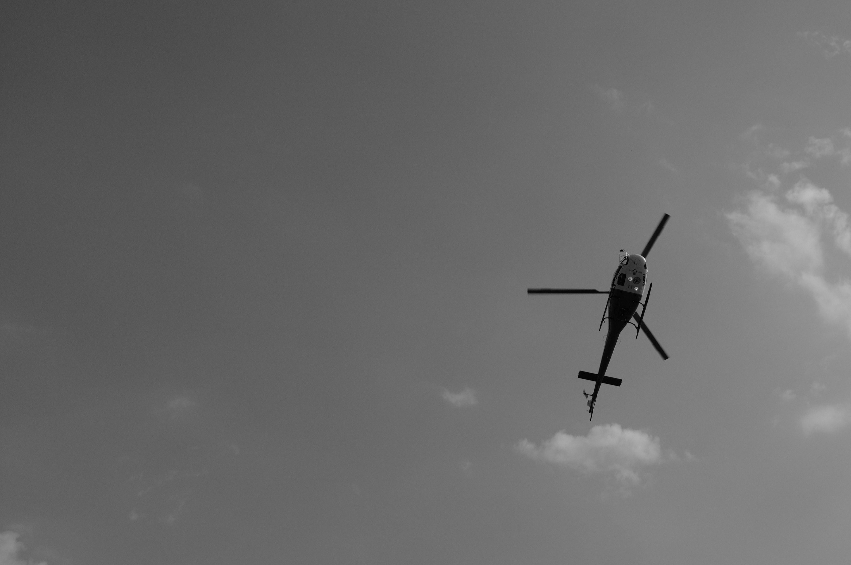 helicopter flying under white clouds